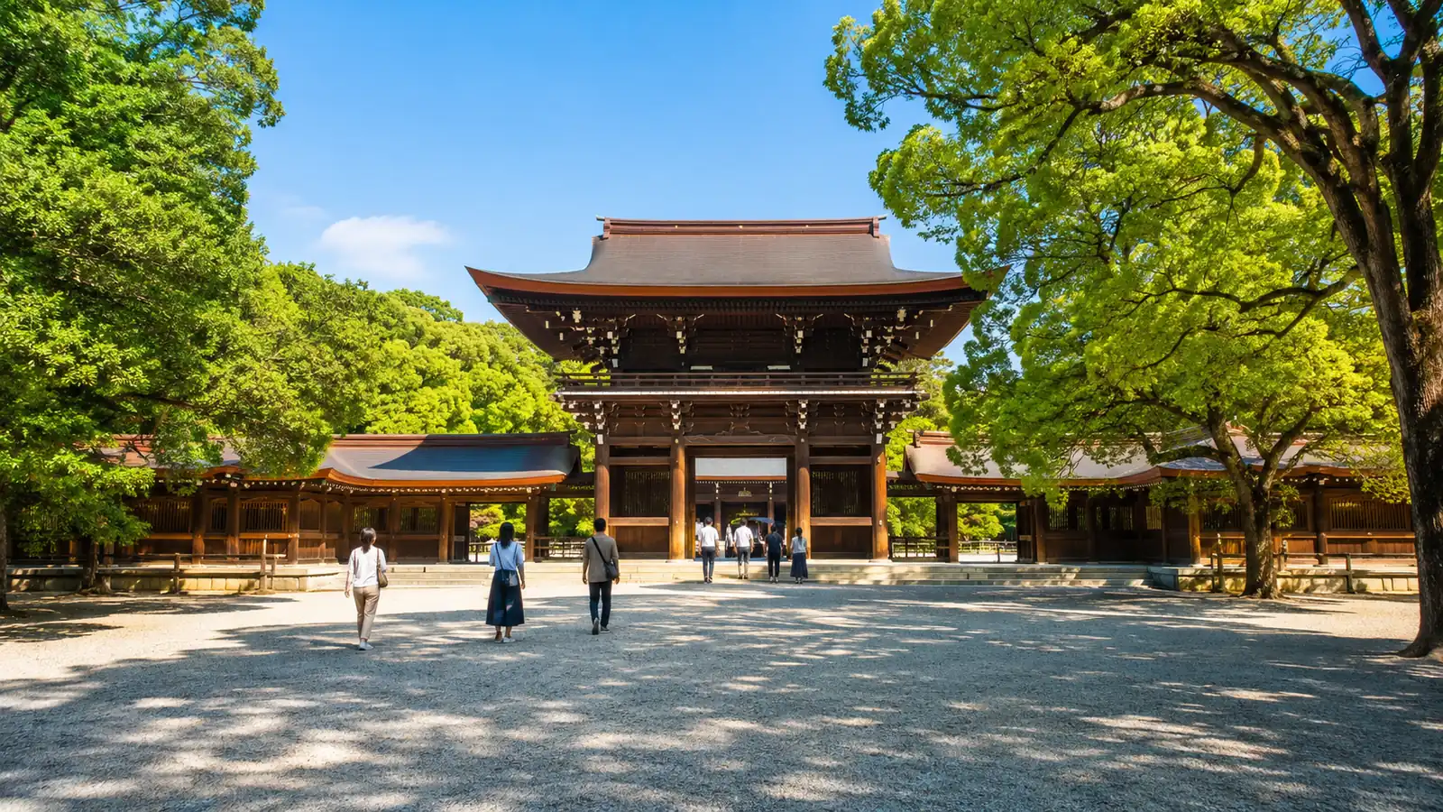 A wide gravel path to a shrine gate on a summer morning, visitors seen from far behind