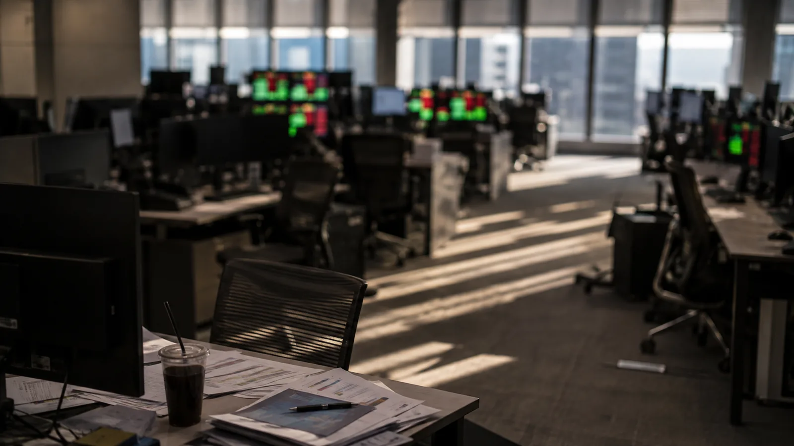 A dealing room in the afternoon, monitors reduced to unfocused red and green glows