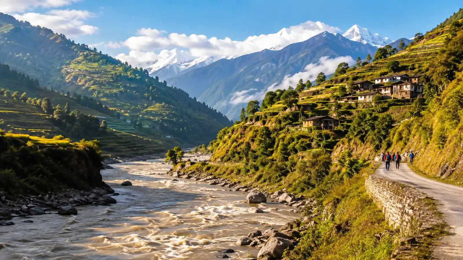 A Himalayan valley in clear morning light, a swollen brown river below green terraced hillsides and a narrow ridge road